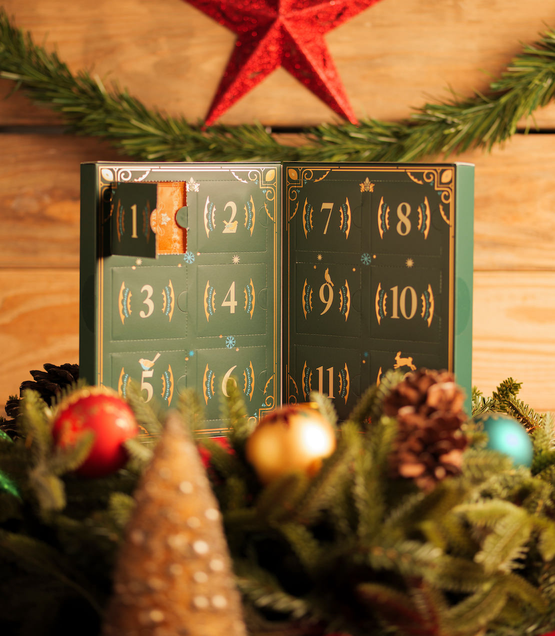 Advent calendar with numbered doors on a wooden background with Christmas decorations.