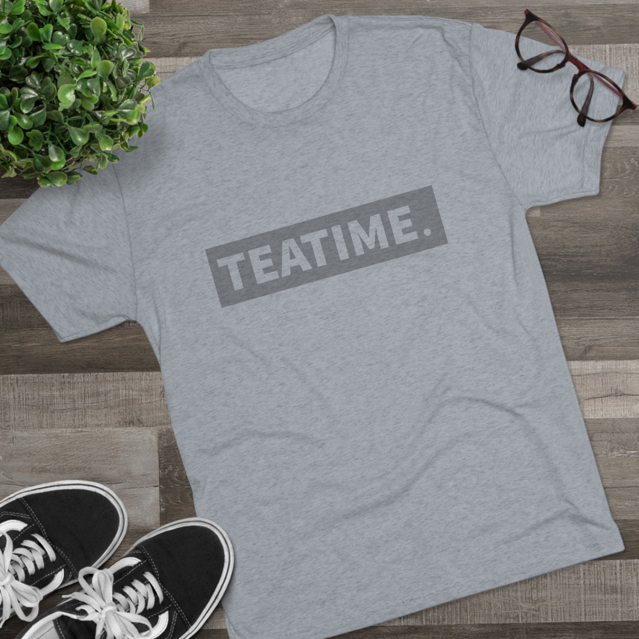 Gray graphic tee featuring the word "TEATIME." in bold letters, styled with casual sneakers and glasses.