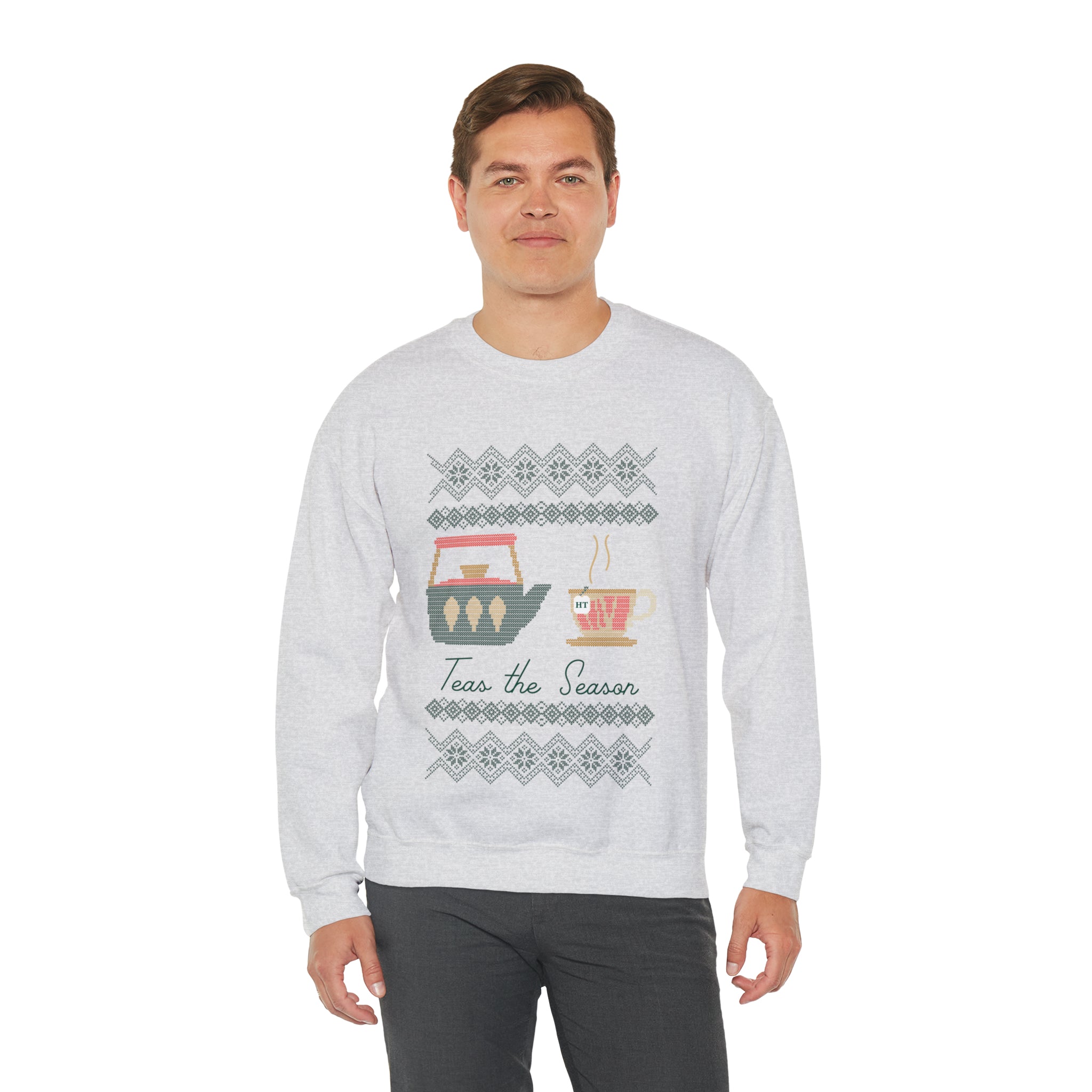 Man wearing a gray holiday sweater featuring "Teas The Season" and festive tea cup graphics.