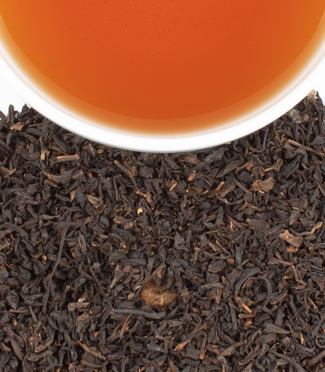 Bag of 50 apricot tea sachets with brewed tea in a cup, surrounded by loose black tea leaves.
