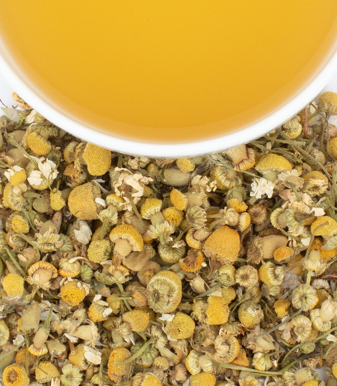 Chamomile tea sachets with dried flowers and brewed tea in a cup, promoting relaxation and wellness.