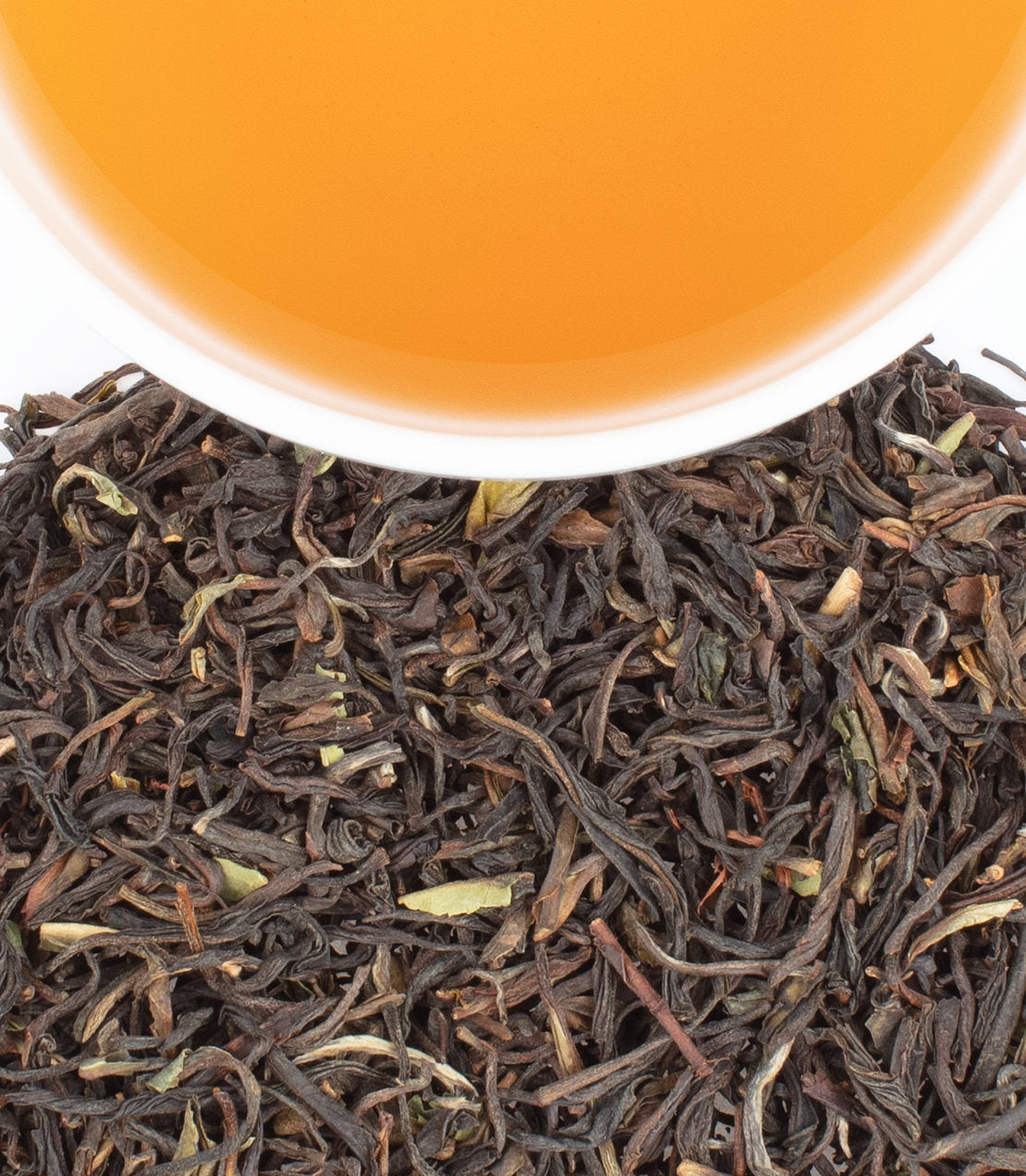 A close-up of Chamraj Black tea leaves with a cup of brewed tea above, showcasing rich color and texture.