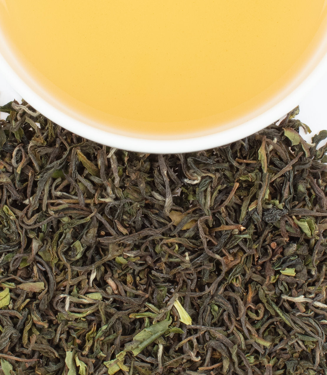 Puttabong 1st Flush Darjeeling tea leaves with a cup of golden-yellow brewed tea above.