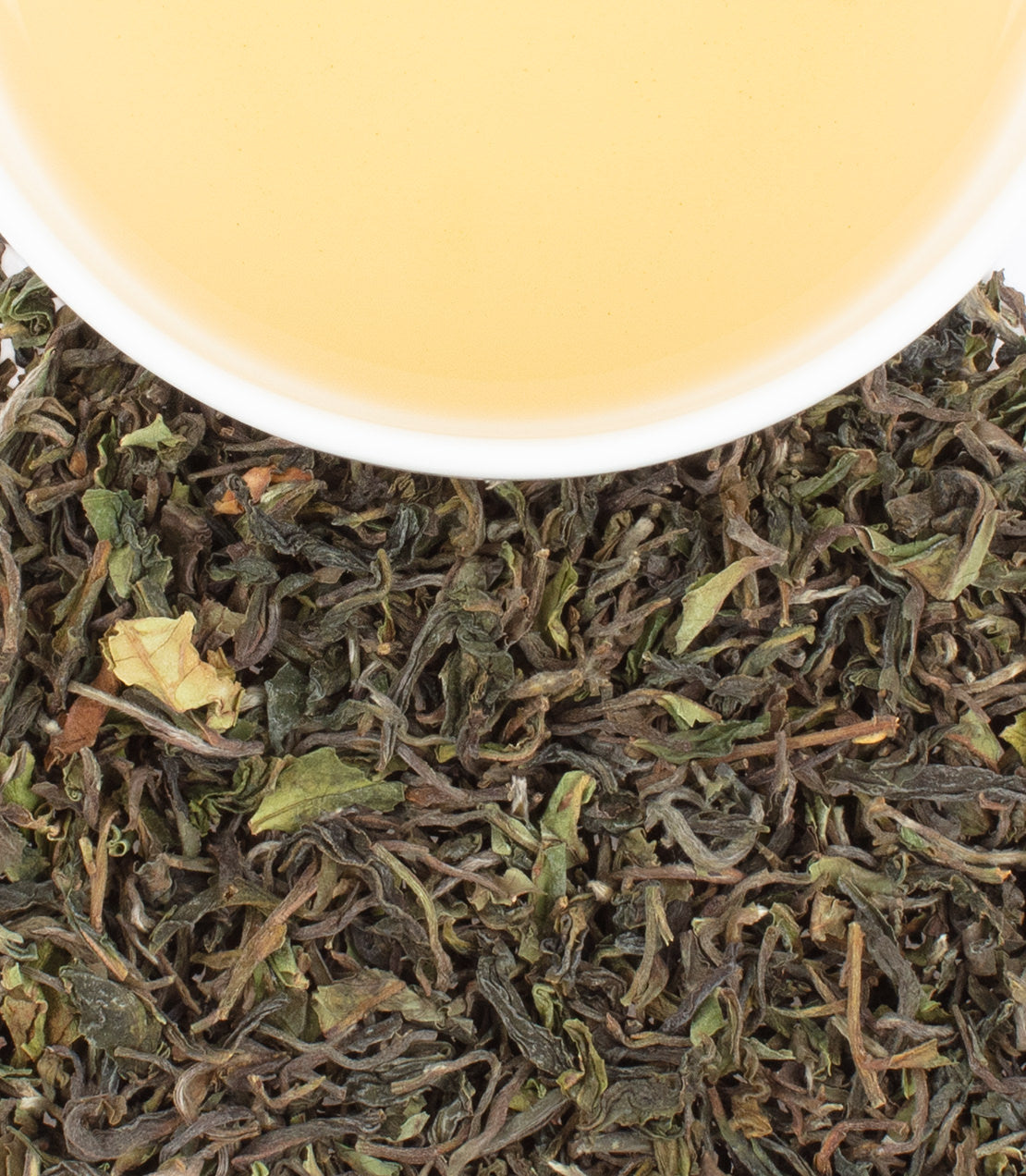 Teesta Valley 1st Flush tea leaves with a cup of light yellow tea, showcasing freshness and quality.