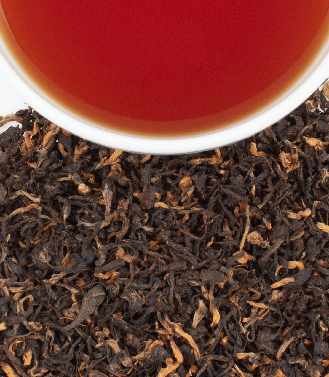 Tonganagaon Full Leaf tea with rich amber liquid above a pile of loose black tea leaves.