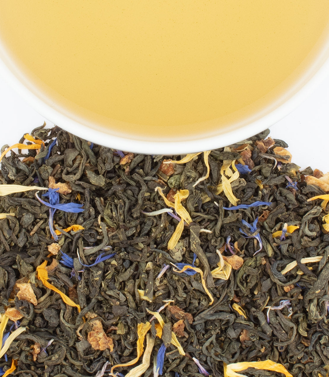 Tea leaves with flowers and a cup of tea in the background
