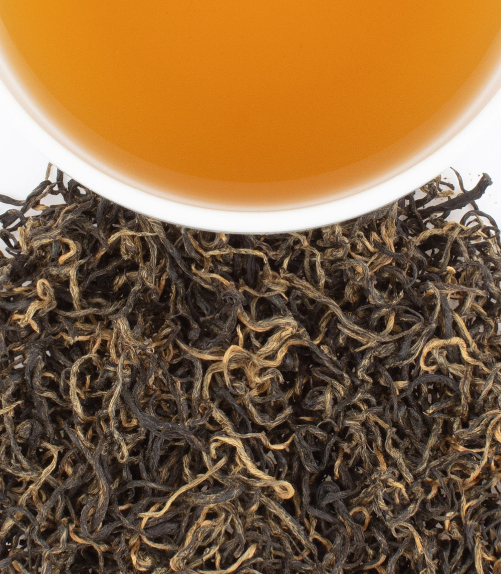 Close-up of BaoMu Gold tea leaves with a cup of brewed tea, showcasing rich colors and textures.