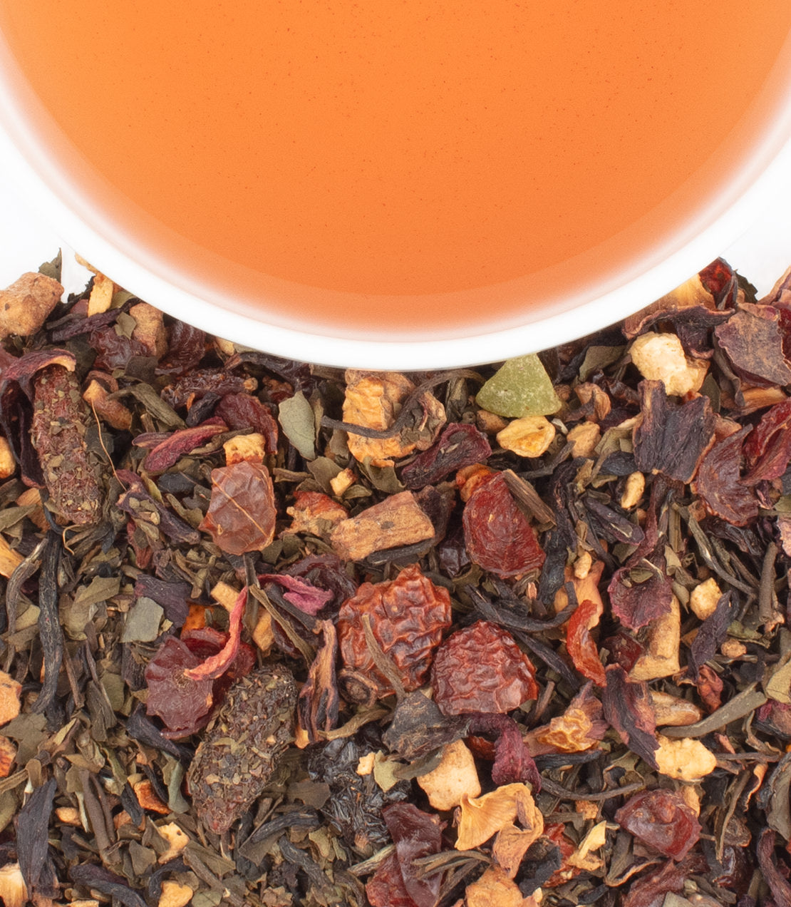 A close-up of Berry Young tea blend with dried fruits and herbs, alongside a cup of brewed tea.