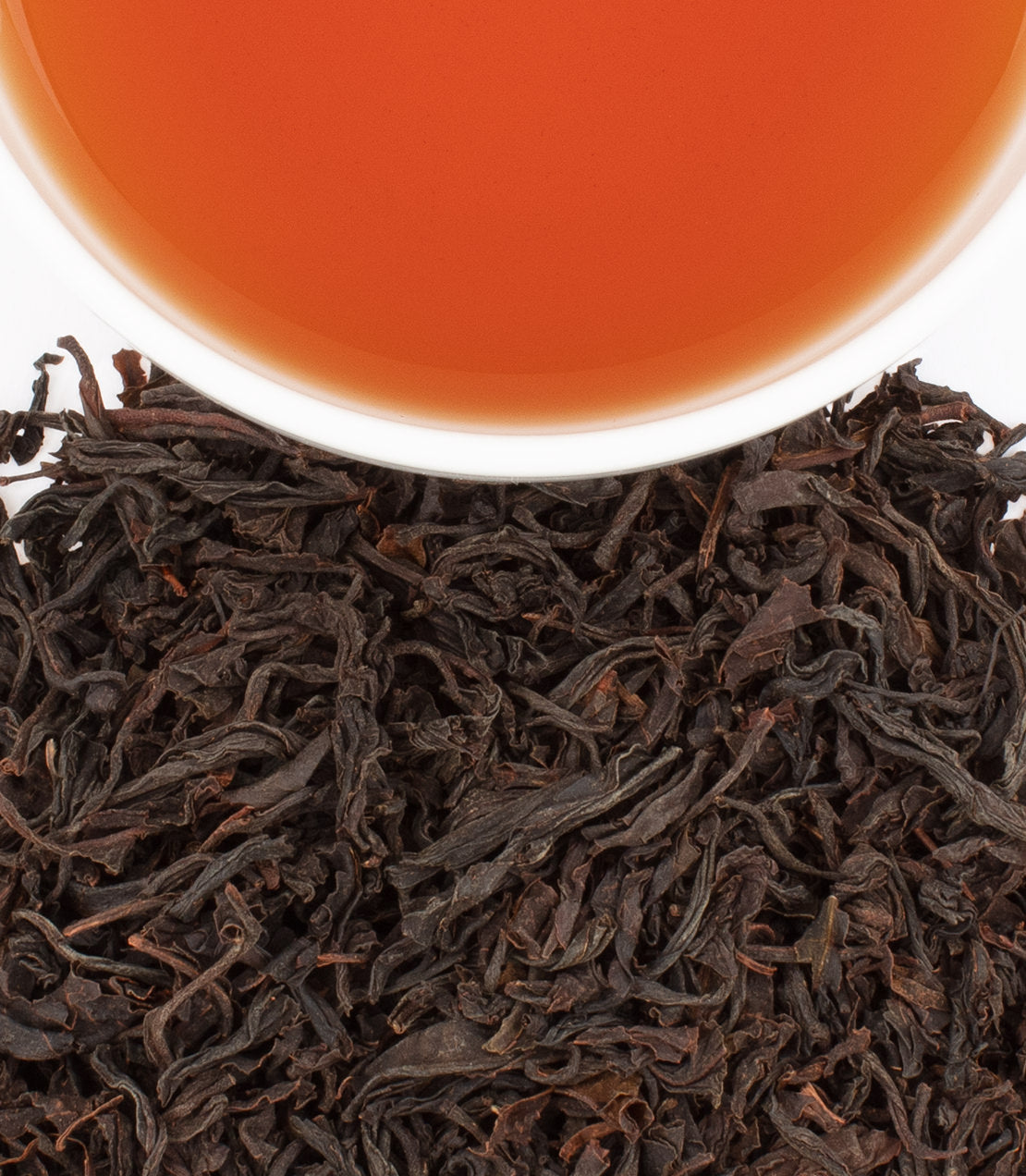 Dunsandle Black tea leaves with brewed tea in a white cup, showcasing rich color and texture.