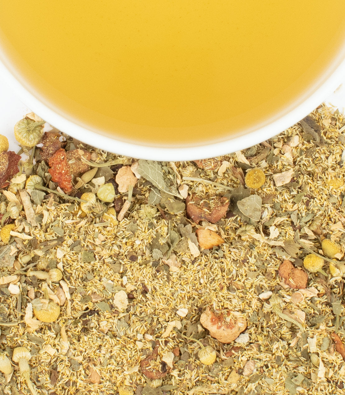 Honey chamomile tea sachets with brewed tea in a cup, showcasing dried herbs and flowers.