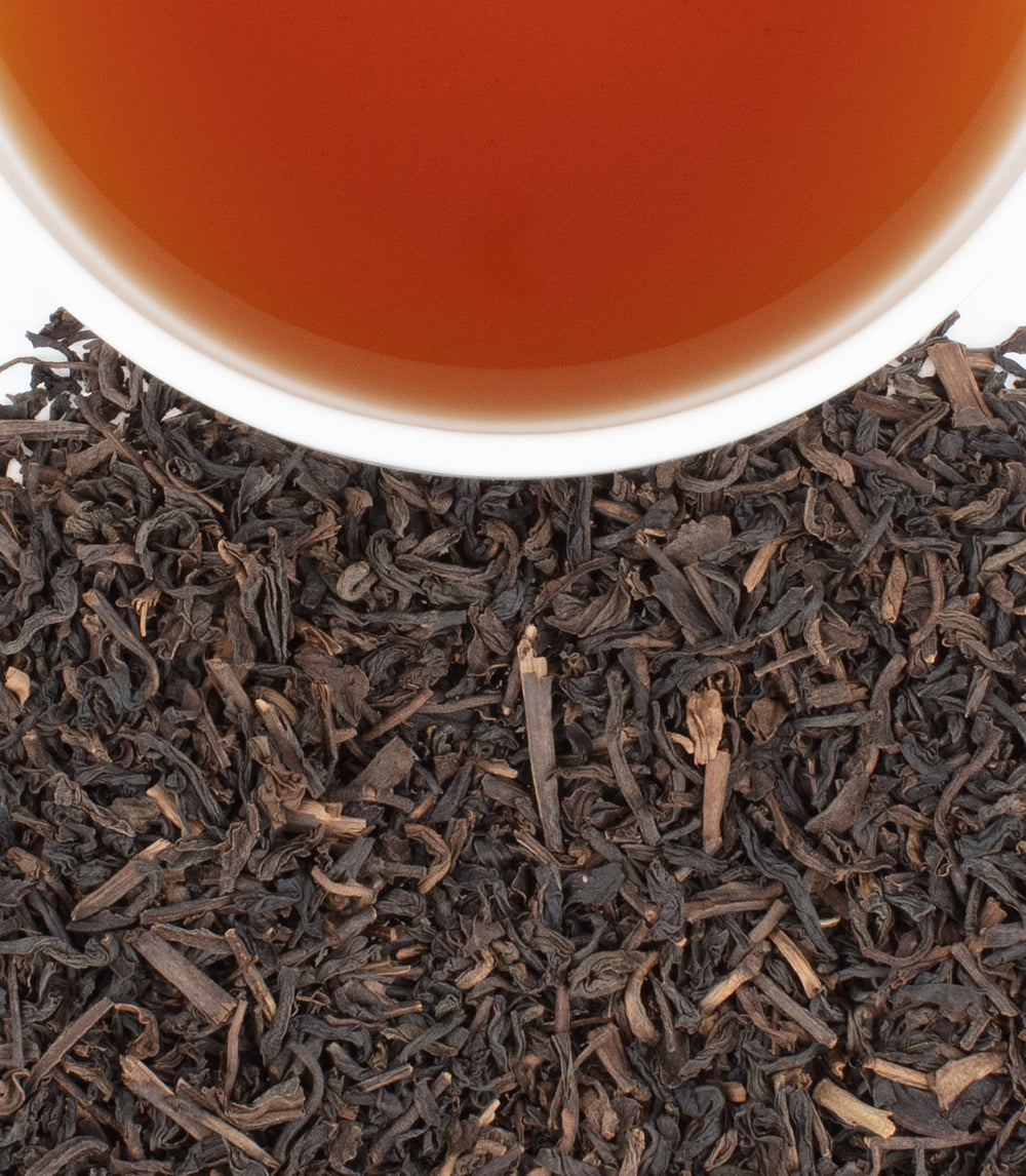 Decaf Ceylon tea sachets, 50-count bag, with brewed tea and loose leaves displayed. Rich flavor and aroma.