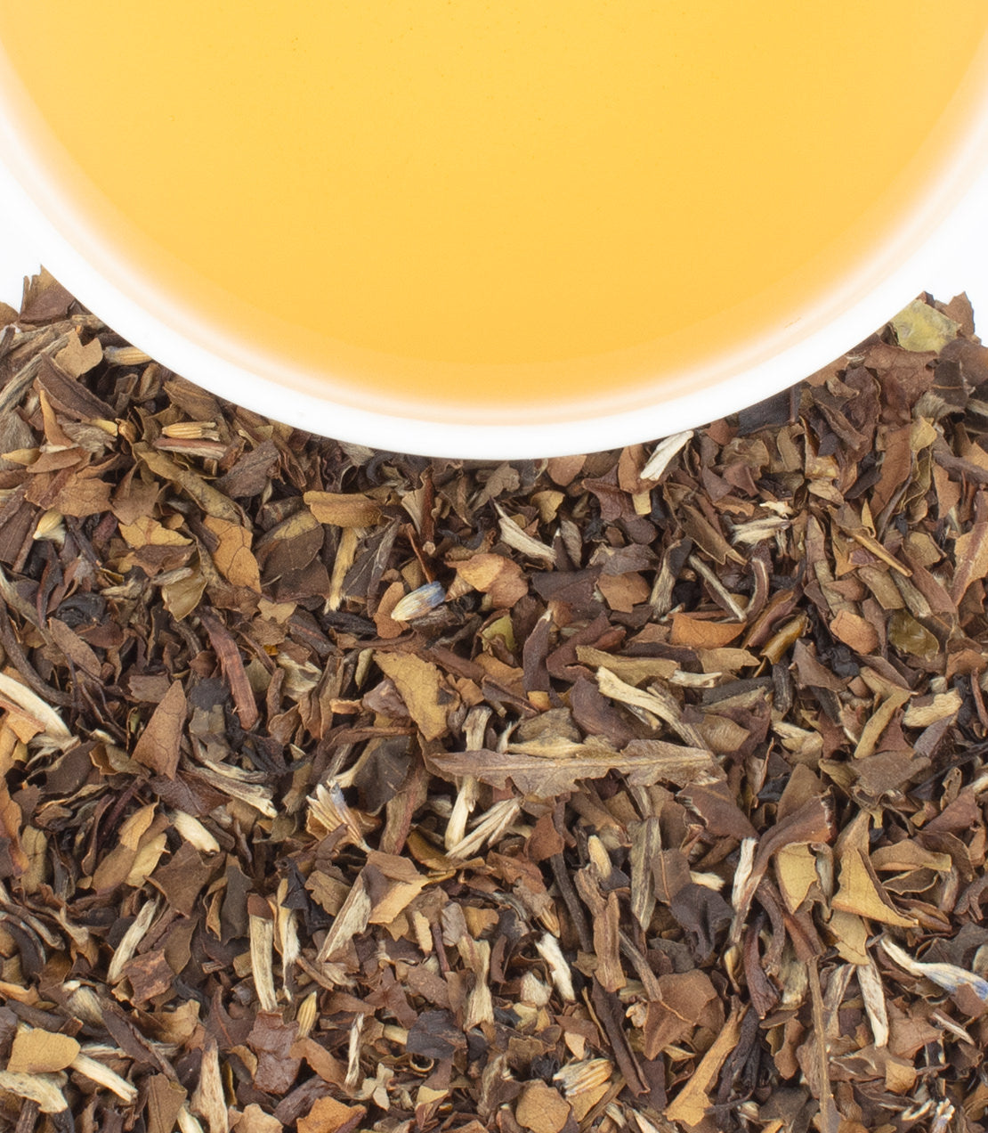 Tin of 20 French Macaron tea sachets with a cup of brewed tea above loose tea leaves.