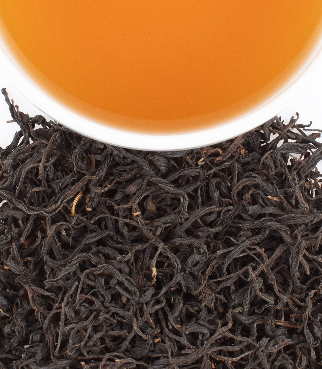 A close-up of Jiuken Black tea leaves with a cup of brewed tea, showcasing rich color and texture.