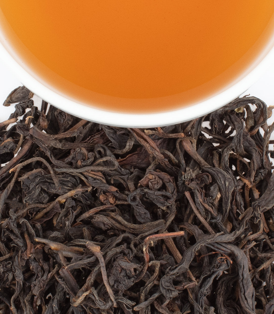 Malawi Black Treasure tea leaves with brewed tea in a white cup, showcasing rich color and texture.