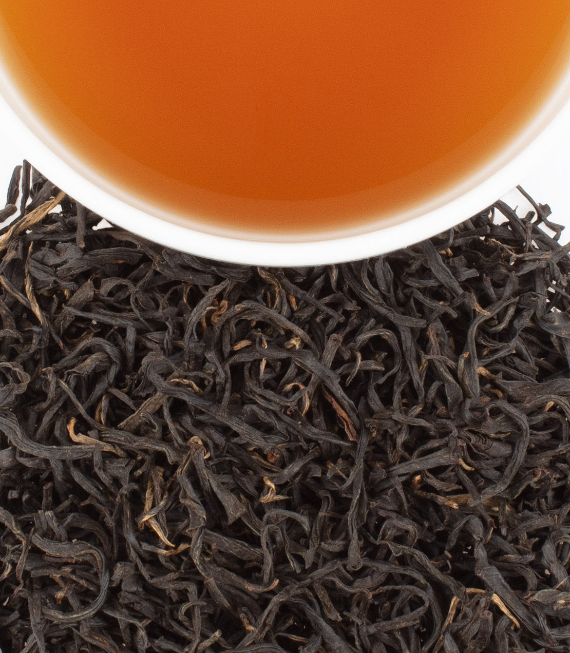 A close-up of Sweet Black Gulou tea leaves with a cup of brewed tea above, showcasing rich colors and textures.