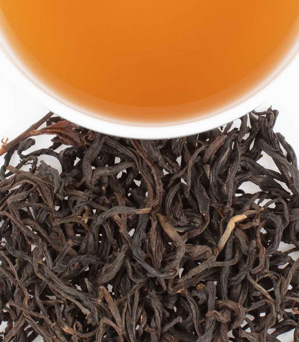 Tanzanian Black tea leaves with brewed tea in a cup, showcasing rich color and texture.