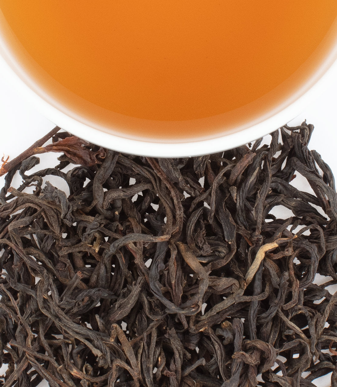 Tanzanian Black tea leaves with brewed tea in a cup, showcasing rich color and texture.