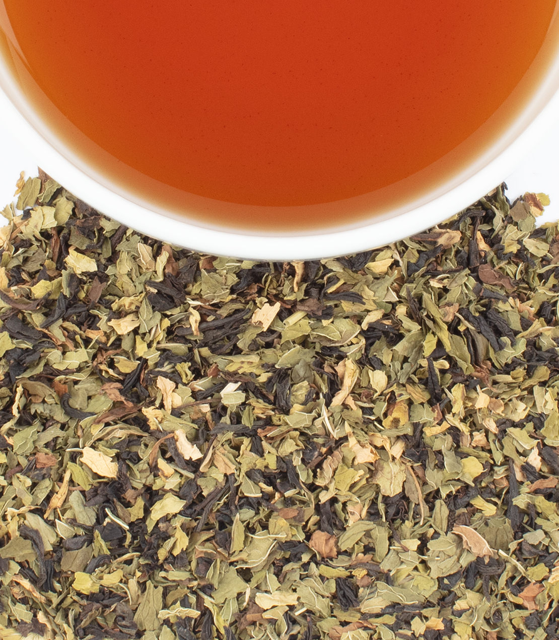 Harney & Sons Fine Teas- Brewed cup of Spearmint Black tea with spearmint and black tea leaves below