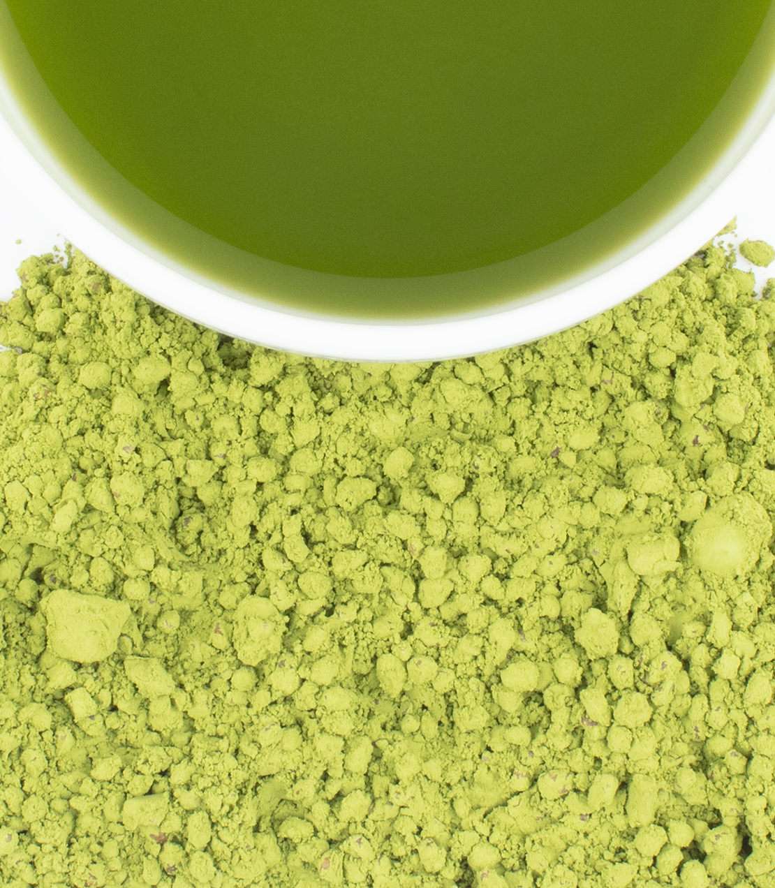 Close-up of bright green matcha powder & buckwheat spread across the bottom half, with a white cup rim and pale green tea visible at the top.