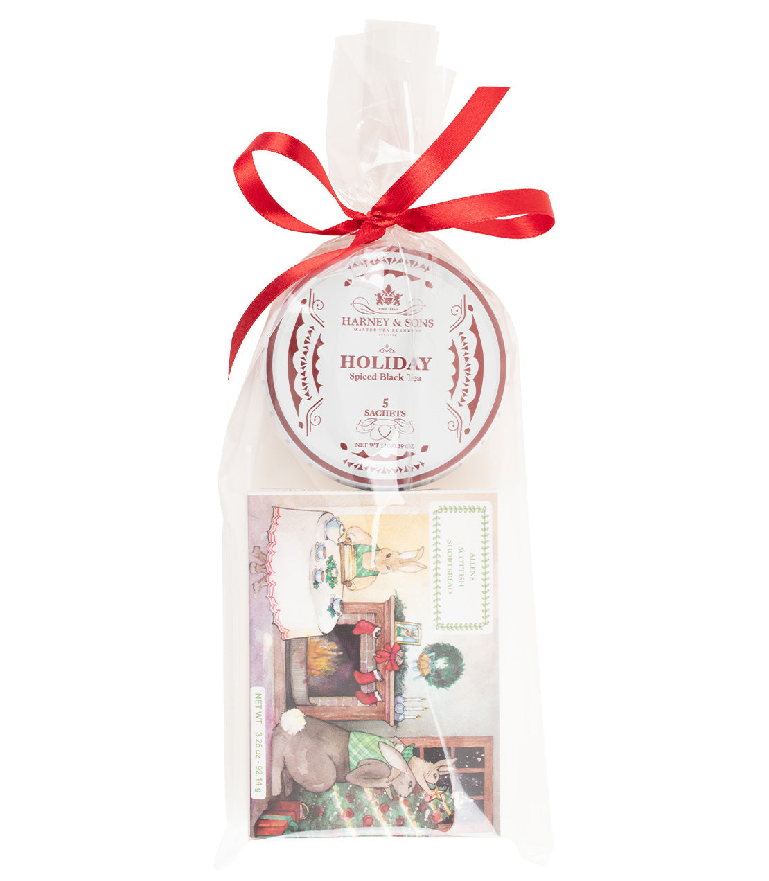 A packaged holiday sweet black tea gift set from Harney & Sons, sealed in a clear cellophane bag tied with a red ribbon. The round white tagalong tin reads 'HARNEY & SONS HOLIDAY Spiced Black Tea' and the box of shortbread features a holiday scene with rabbits