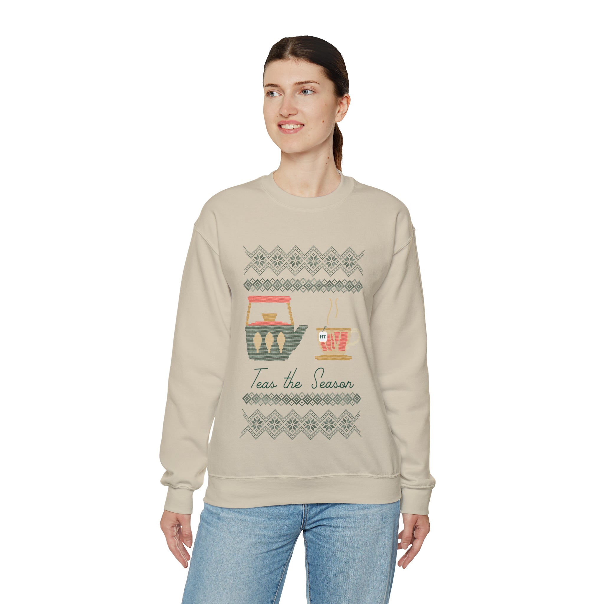 Woman wearing a beige holiday sweater with "Teas The Season" graphic and festive tea-themed designs.