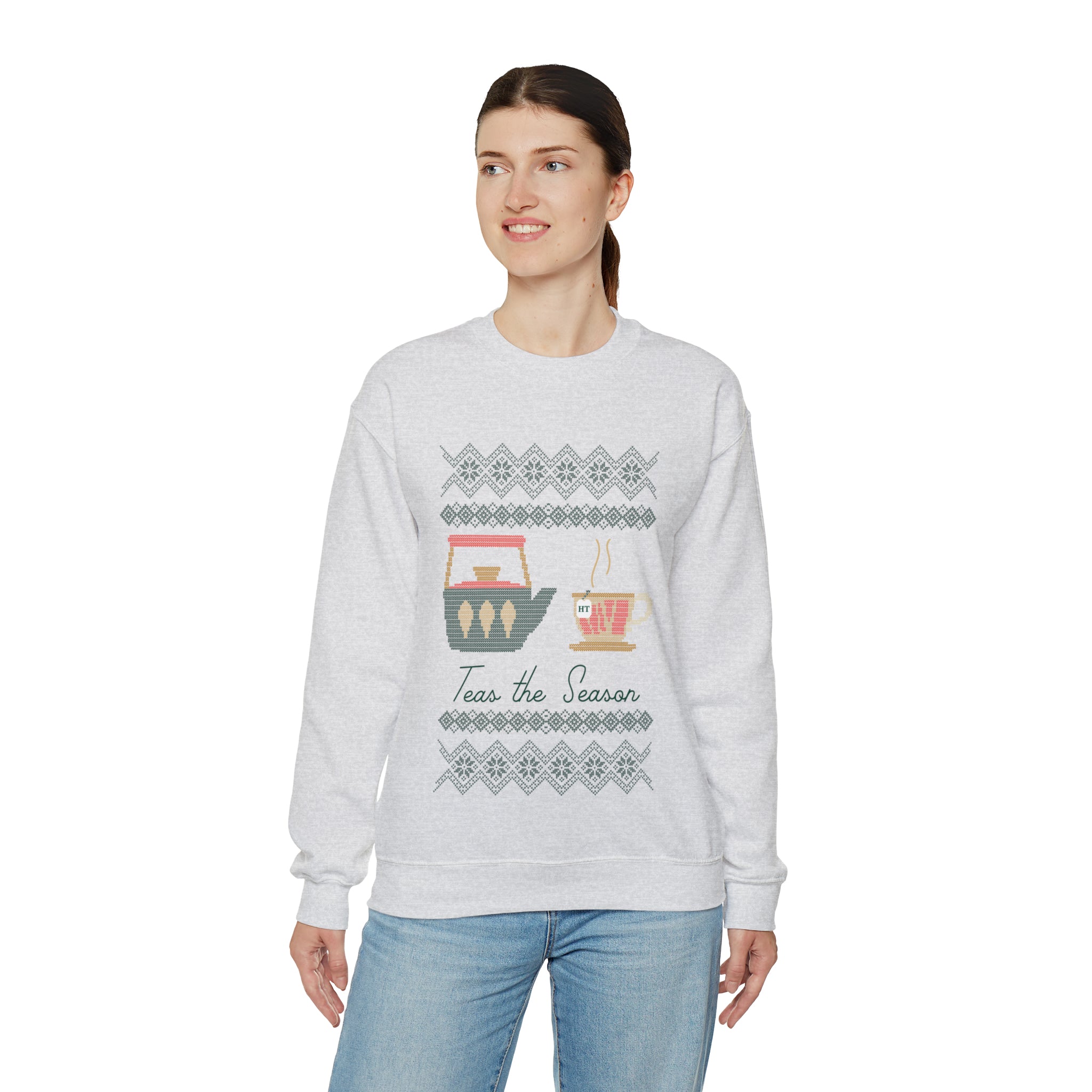 Woman wearing a light gray holiday sweater with "Teas the Season" graphic and festive tea-themed design.