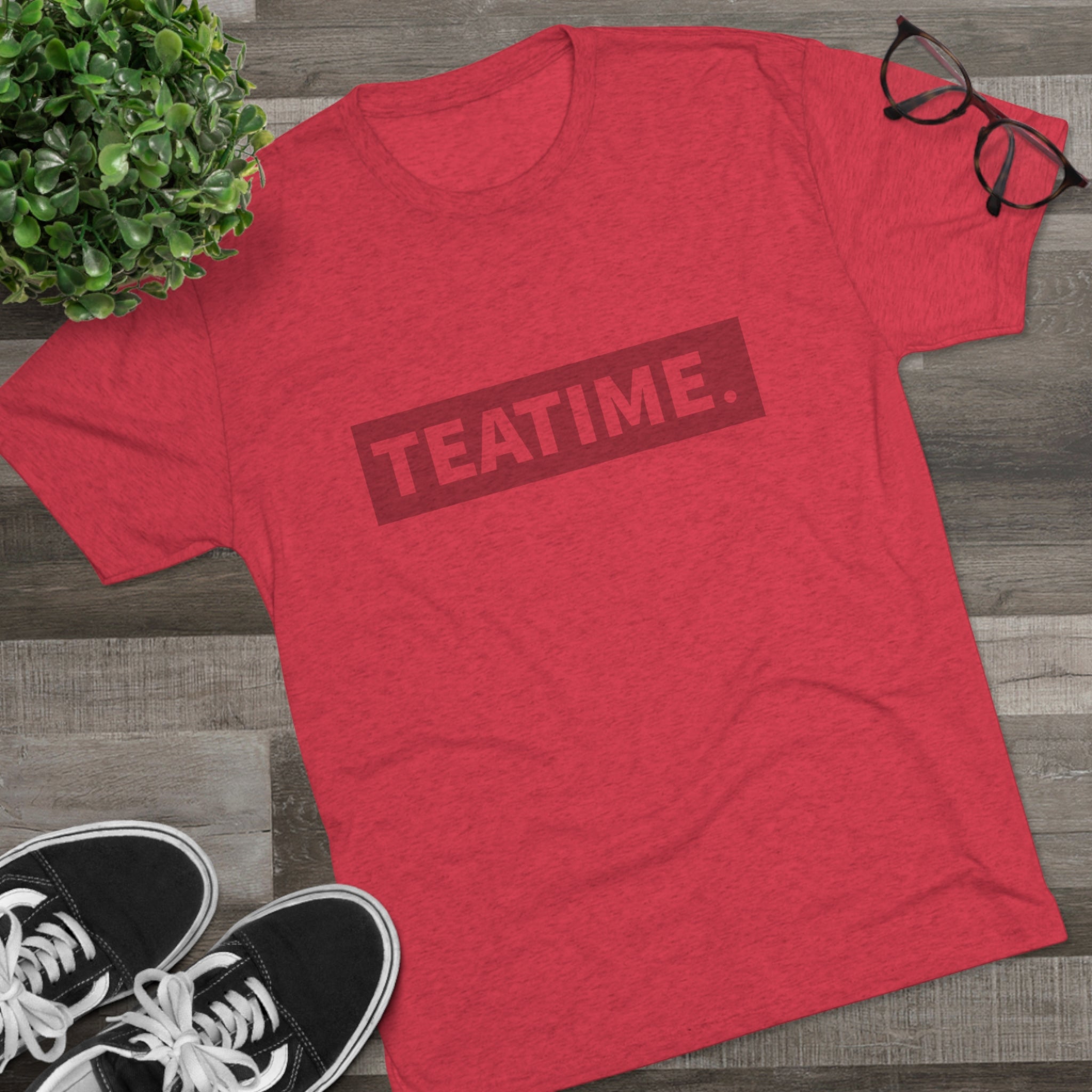Red graphic tee featuring the word "TEATIME." in bold letters, styled with casual sneakers and glasses.
