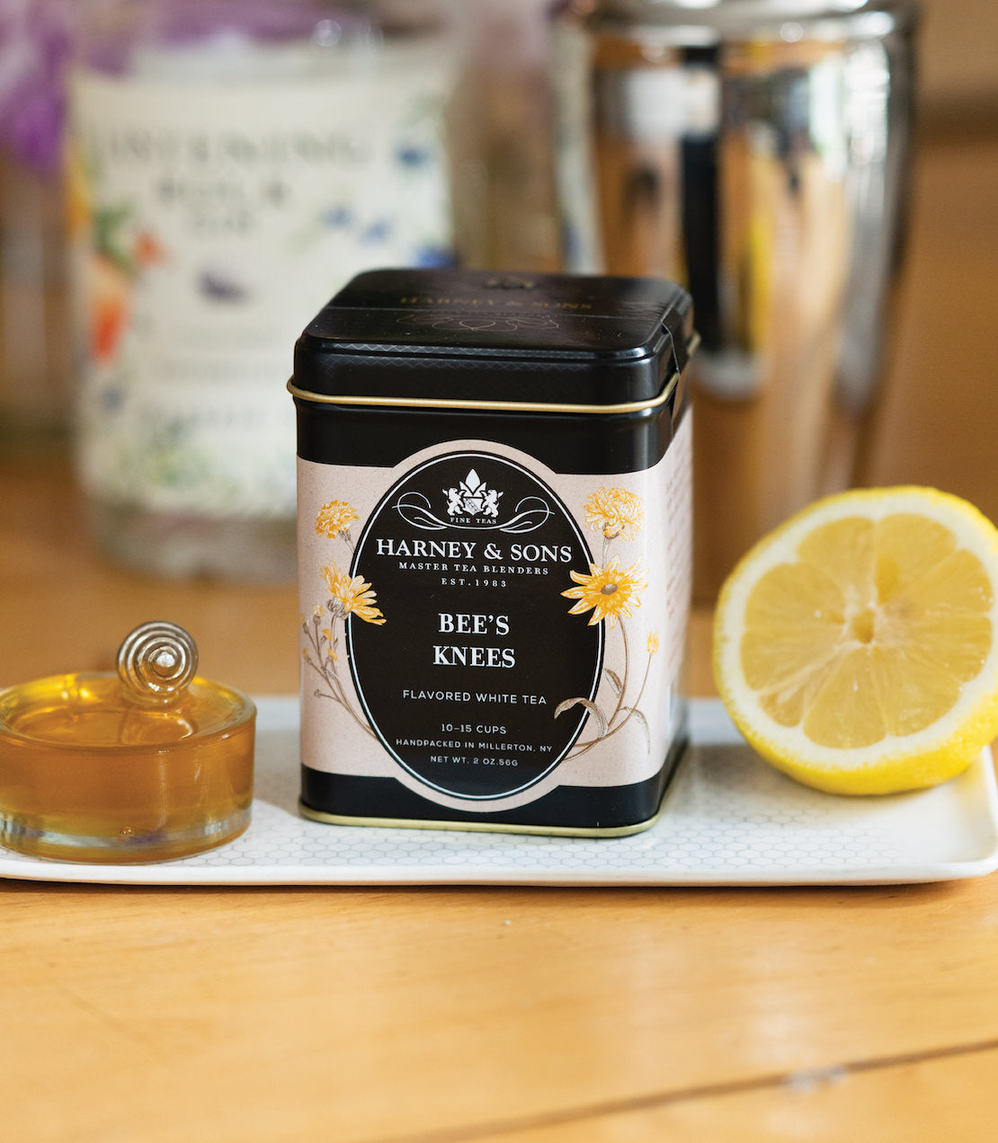 Harney & Sons Bee's Knees flavored white tea tin with lemon and honey on a white tray.