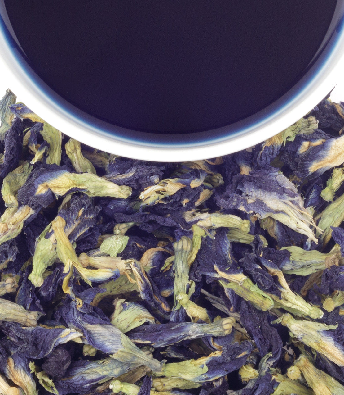 Dried butterfly pea flowers with a cup of brewed blue tea above