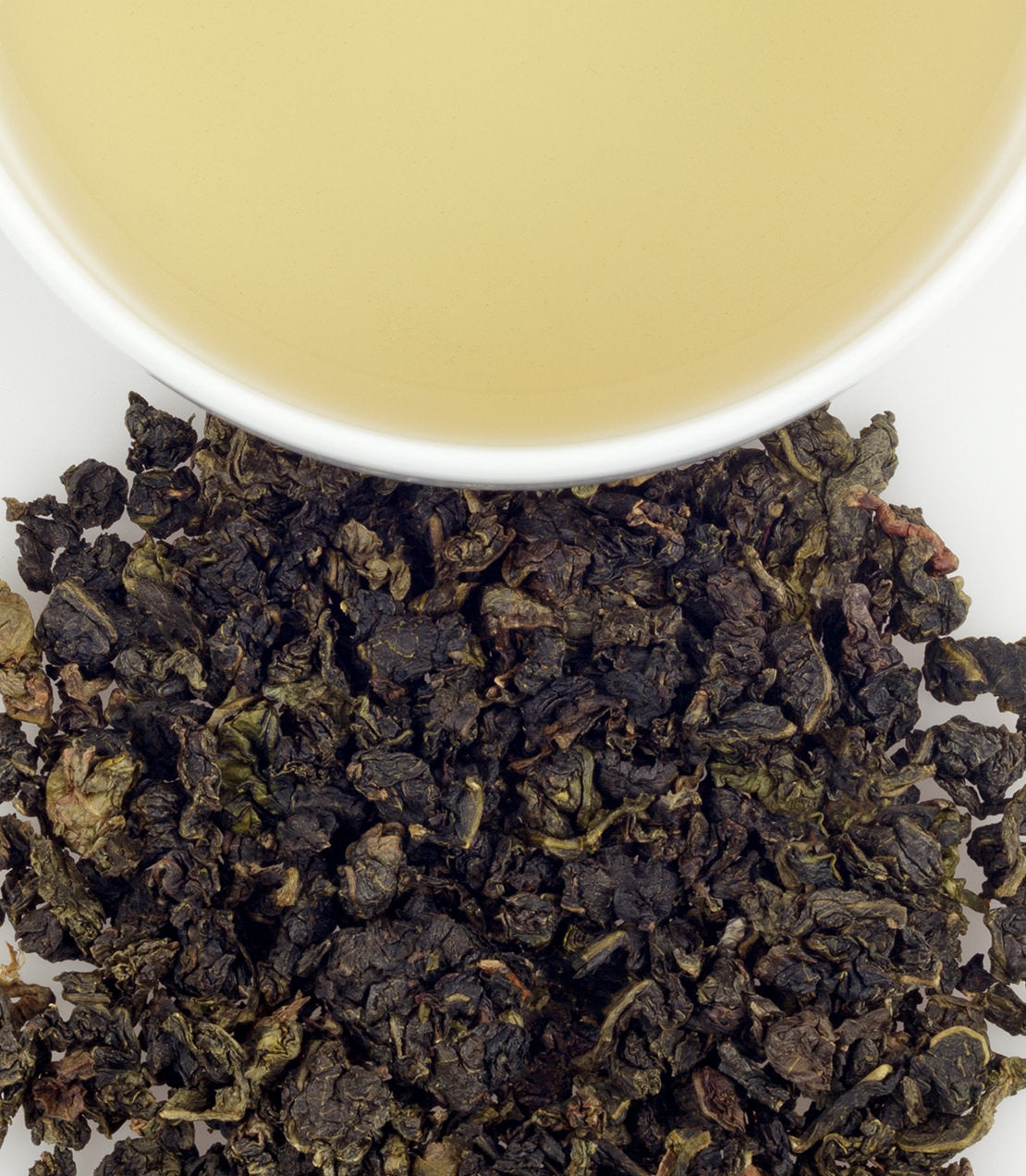 Milky Oolong tea sachets with brewed tea in a cup, showcasing dark green leaves and light yellow liquid.