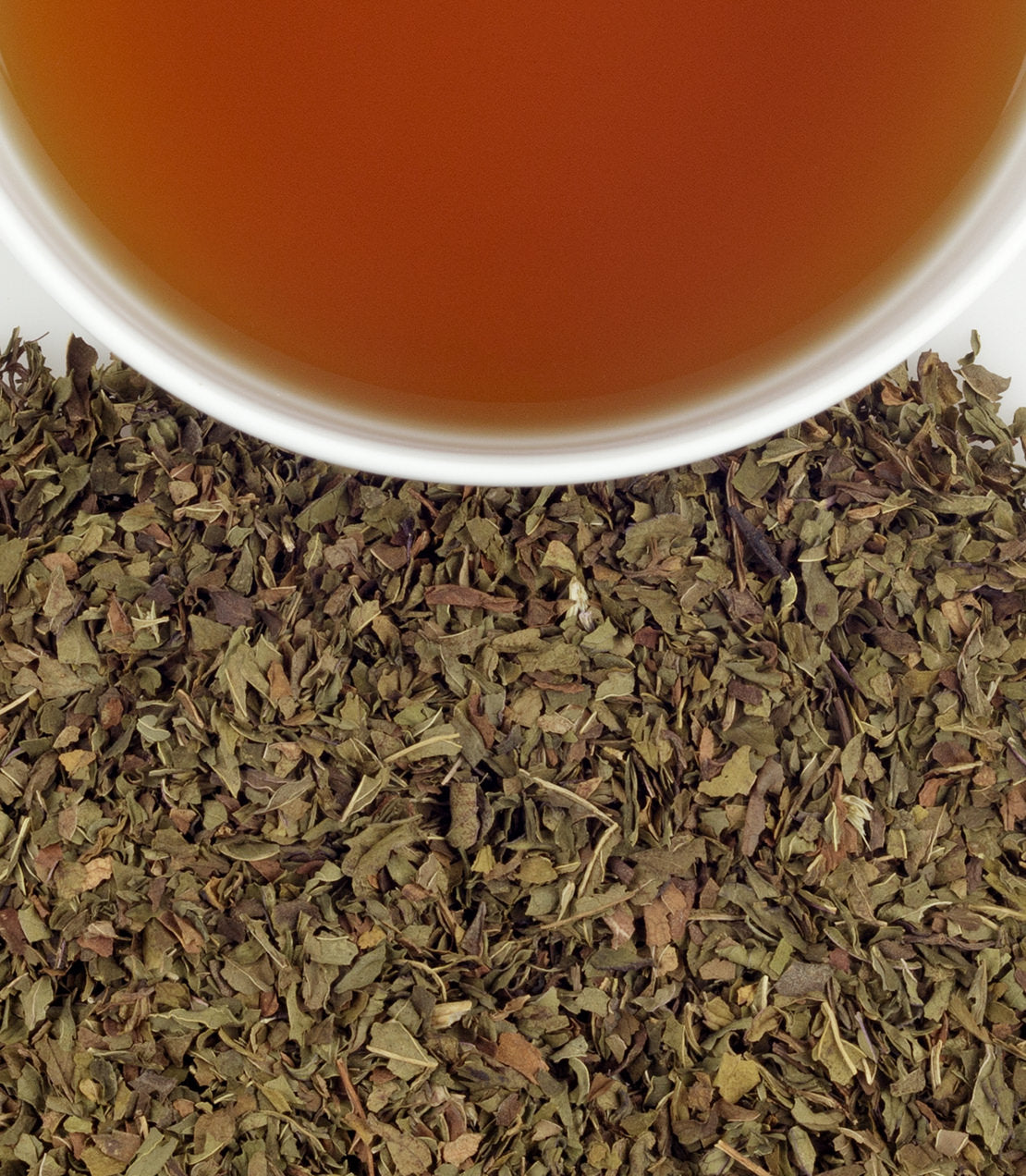 Overhead view of a cup of brewed Organic Peppermint Herbal above dried organic peppermint leaves.