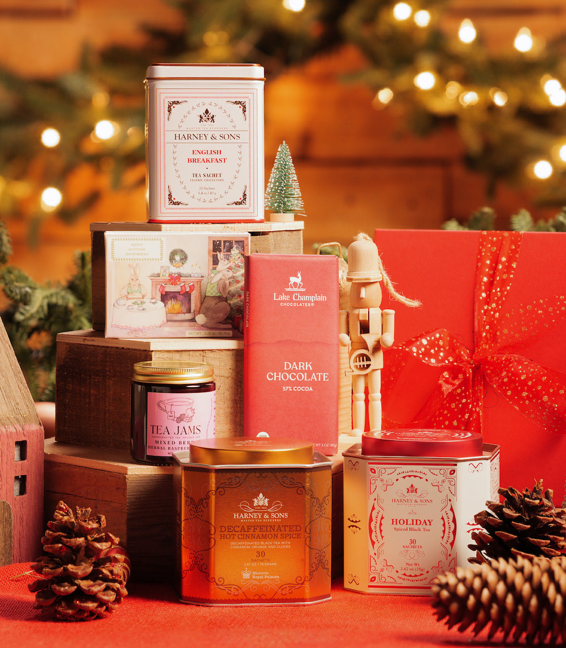 Festive holiday gift set featuring candles, tea, and jams, arranged with lanterns and decorative elements.