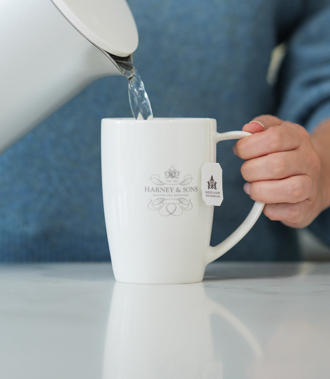White mug with Harney & Sons logo being filled with water from a kettle.