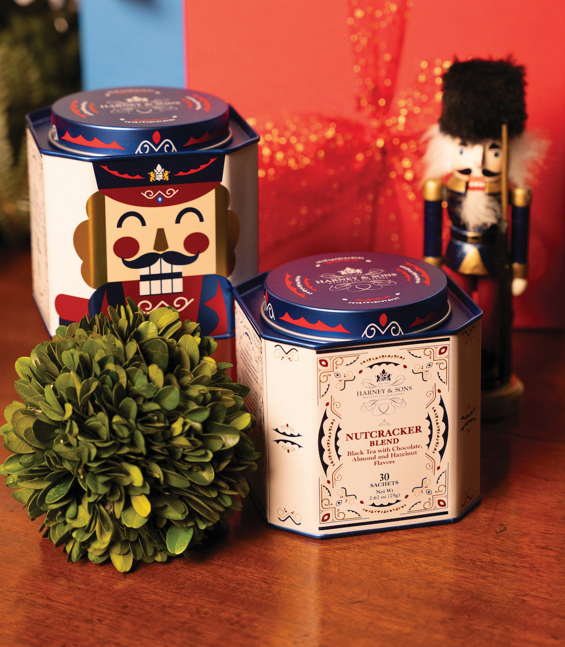 Nutcracker Blend tea tin with 30 sachets, featuring festive design and nutcracker figurine in background.