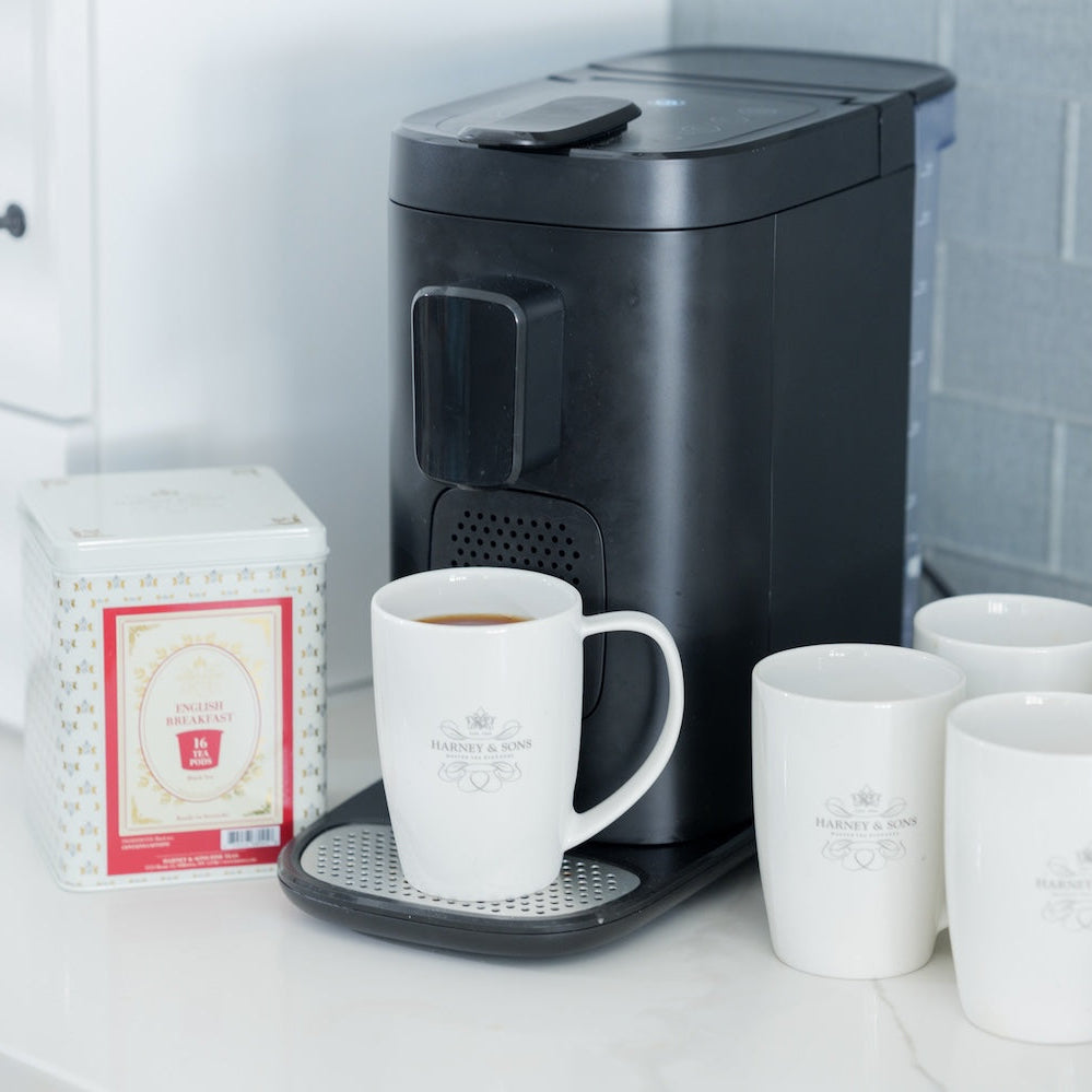 Black Keurig coffee maker with white mugs on a kitchen counter