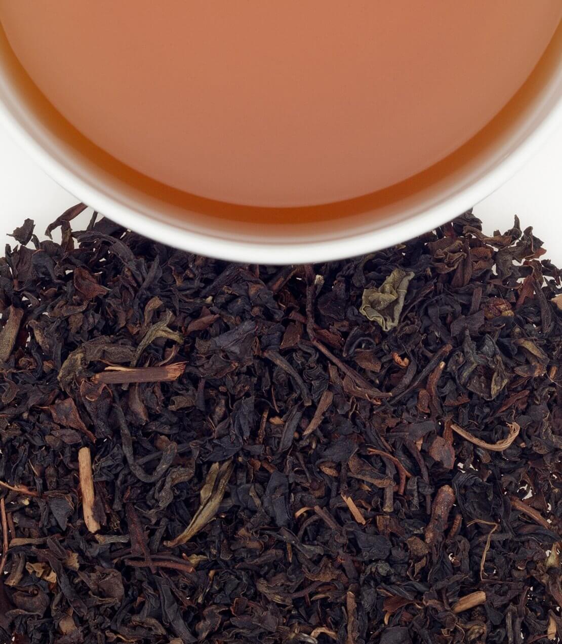 Formosa Oolong tea sachets with brewed tea in a cup, showcasing rich color and loose leaf texture.