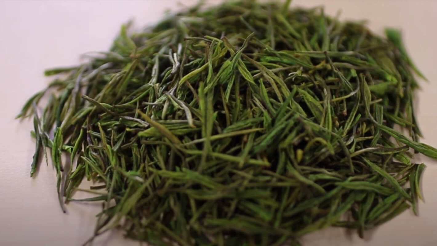 Loose green tea leaves with slender, twisted, and vibrant green appearance, perfect for premium tea brewing.
