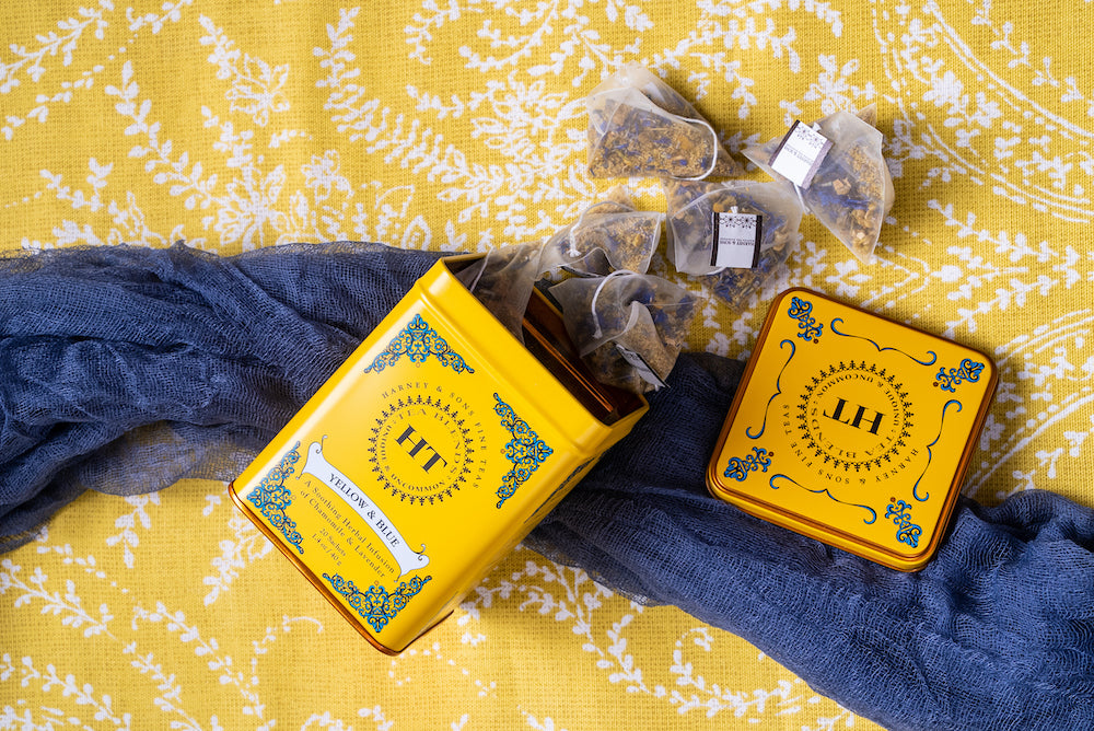 Yellow & Blue tea tin with tea sachets on a yellow and white patterned fabric