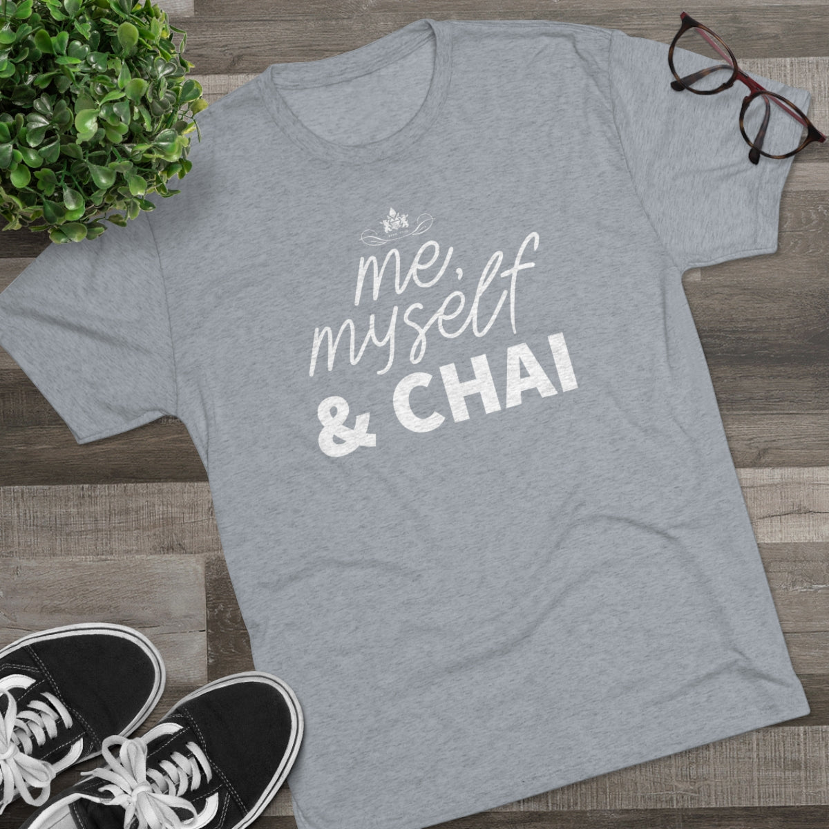 Gray graphic tee featuring the text "me, myself & CHAI" in white, styled with casual sneakers and glasses.