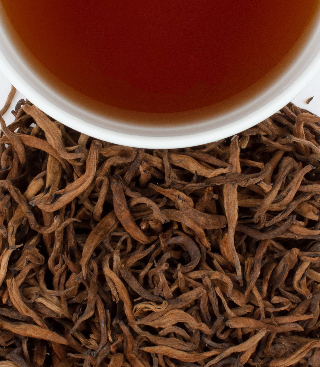 Golden Pu-Erh tea leaves surround a cup of brewed tea, showcasing rich colors and textures.