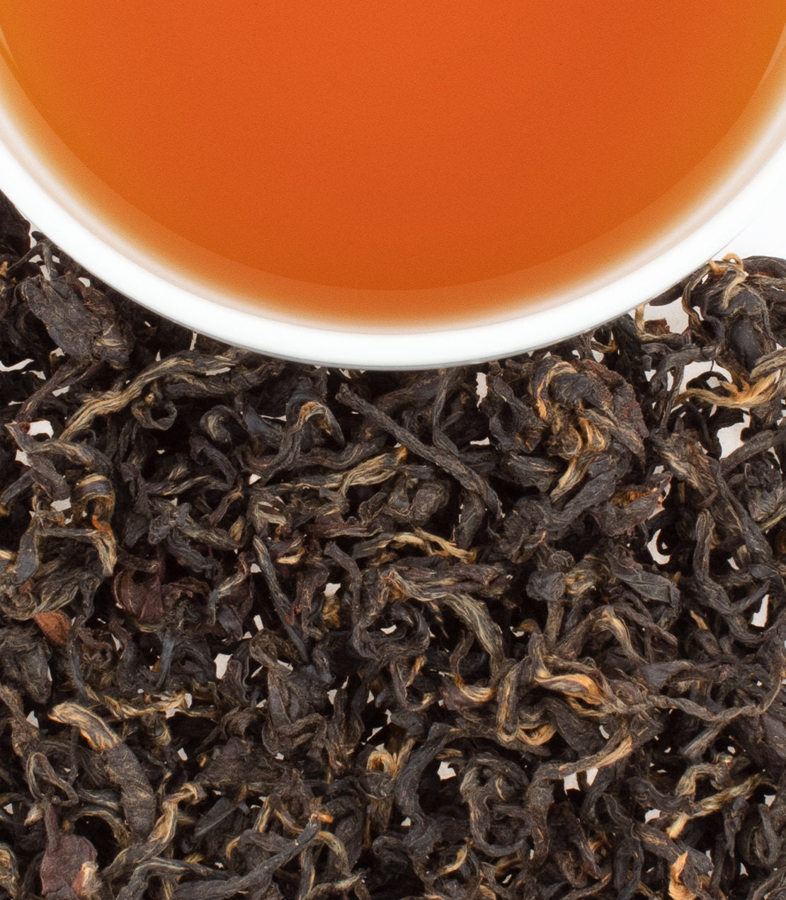 Hawaiian Black Dragon tea leaves with brewed tea in a white cup, showcasing rich color and texture.