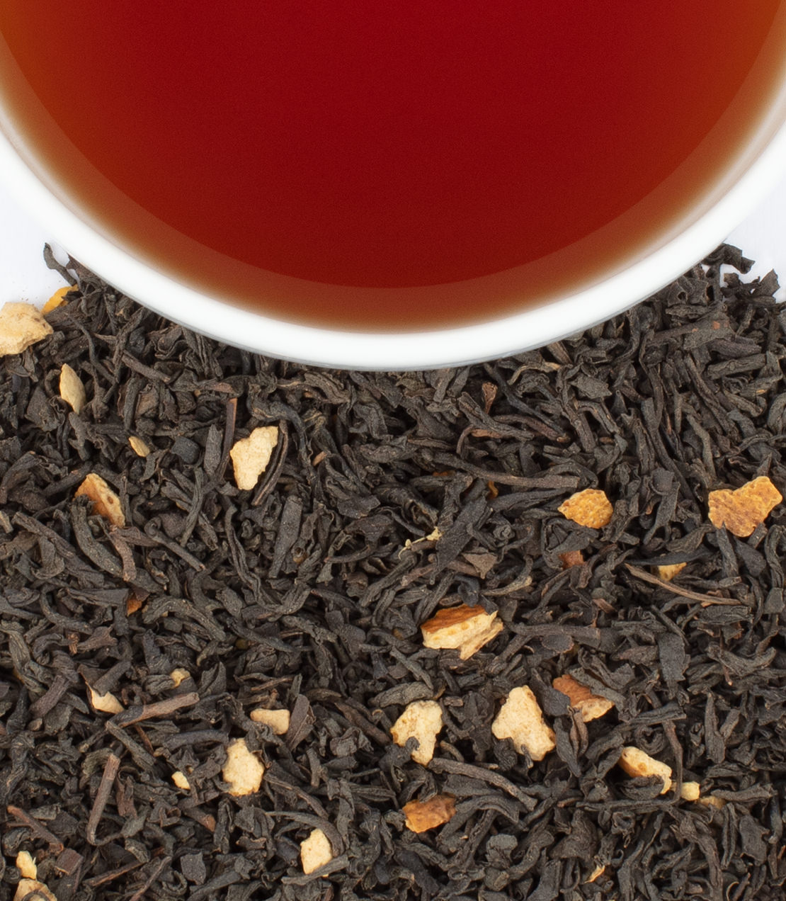 Williamsburg Ginger Cake tea sachets with brewed tea in a cup, showcasing black tea and ginger pieces.