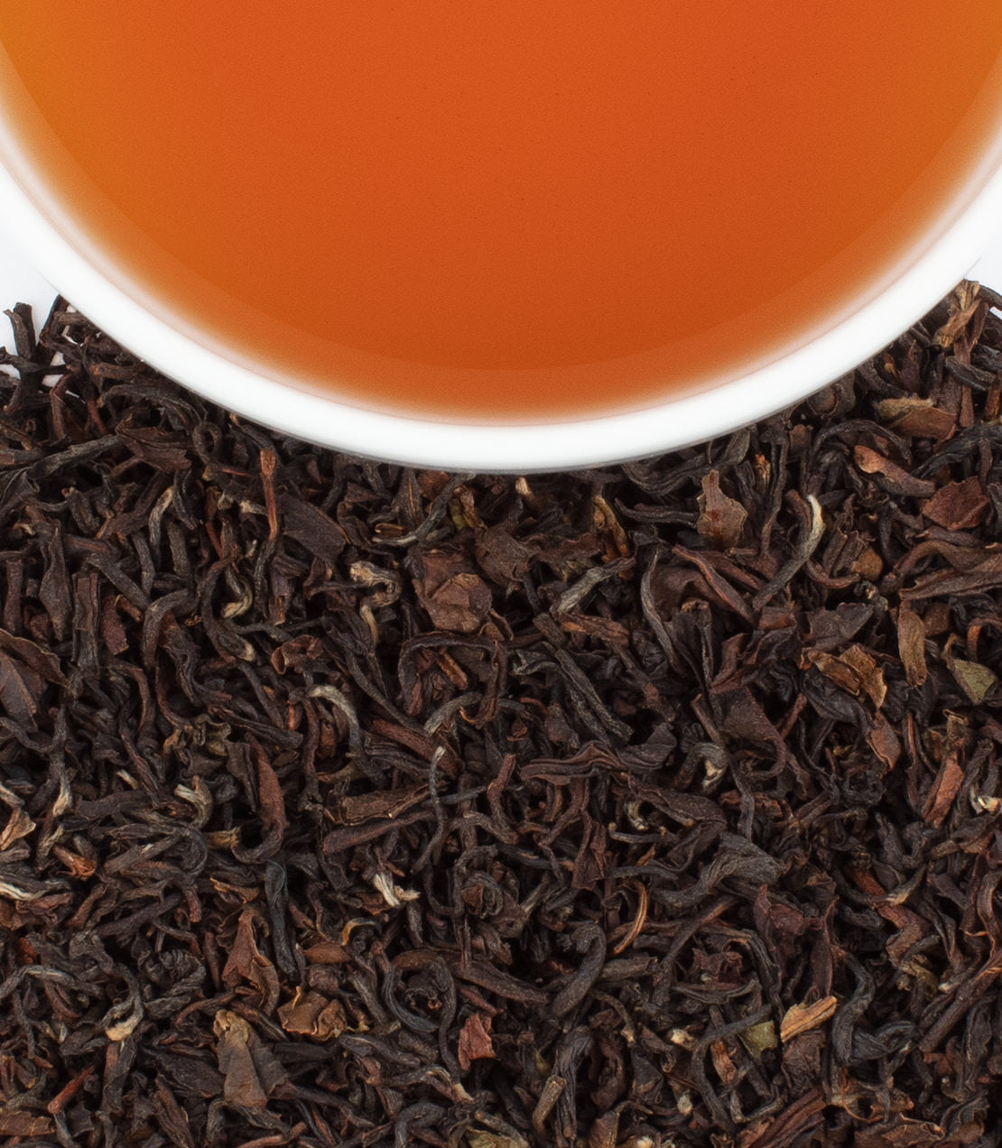 Tumsong 2nd Flush Darjeeling tea leaves with a cup of brewed amber tea, showcasing rich color and texture.