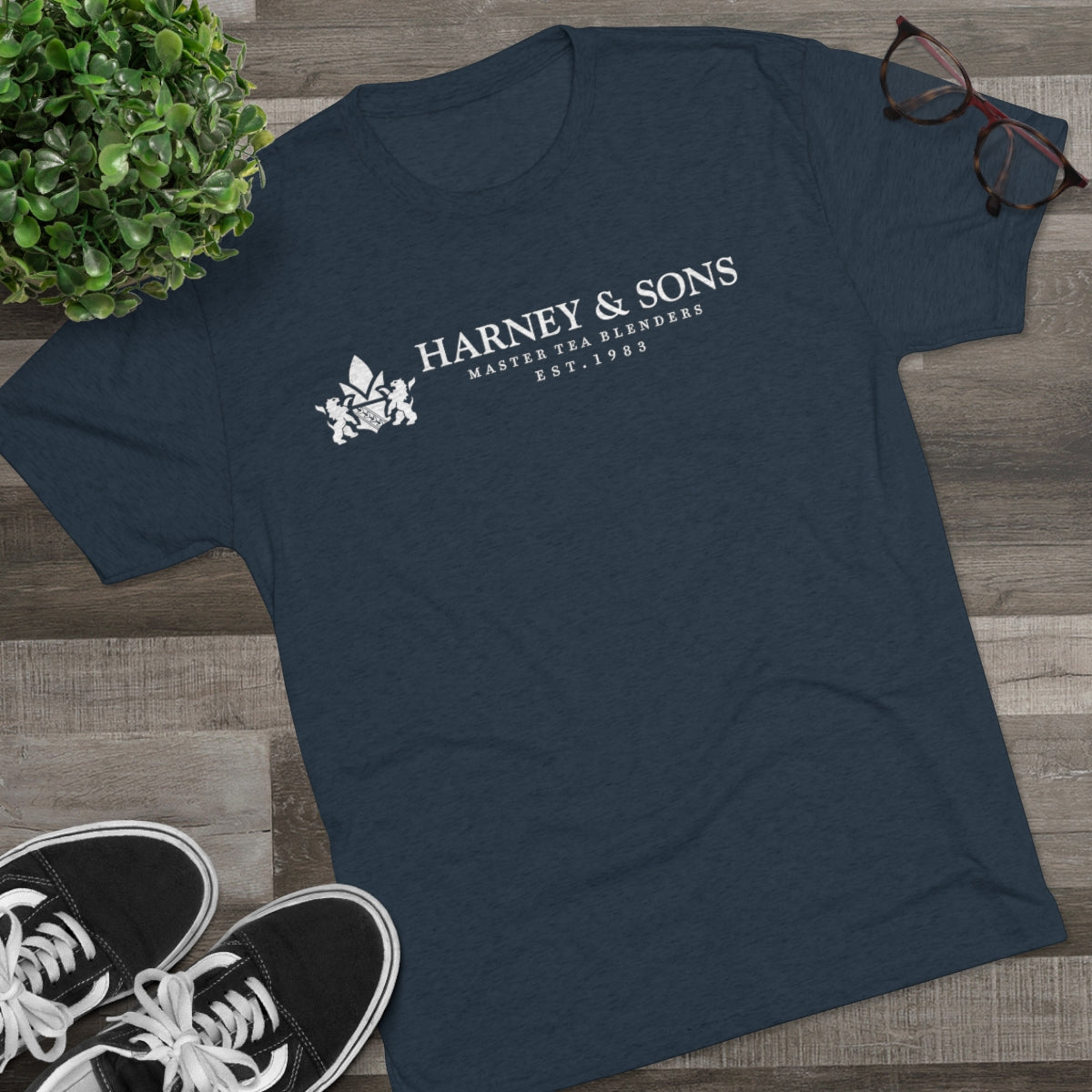 Navy graphic tee featuring "Harney & Sons Master Tea Blenders Est. 1983" text, styled with casual shoes and glasses.