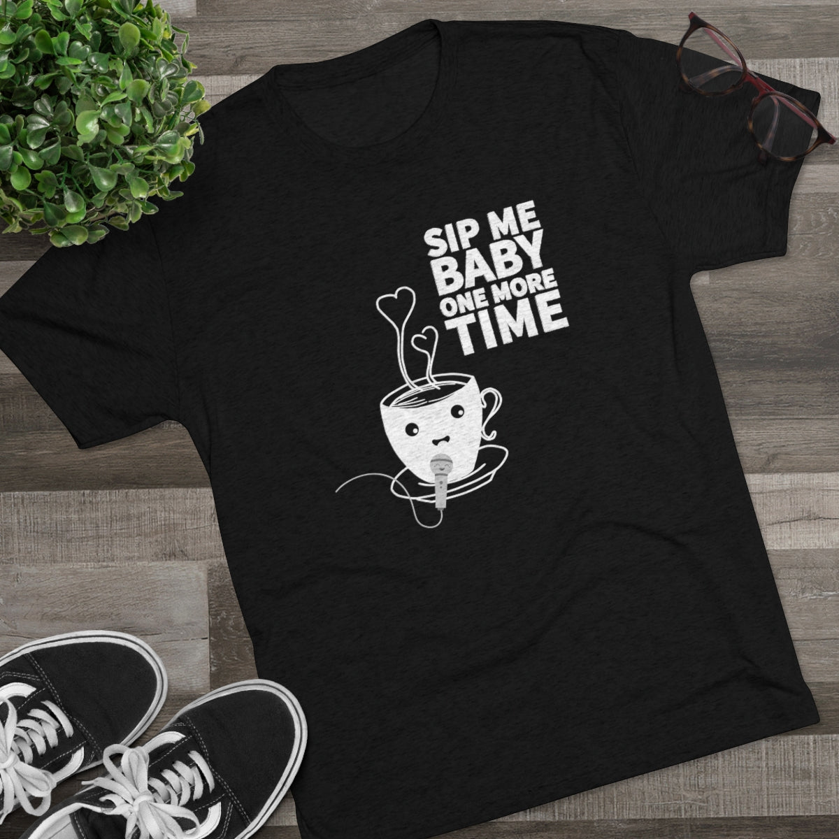 Black graphic tee featuring a cute coffee cup with a microphone and the text "Sip Me Baby One More Time." Perfect for coffee lovers.