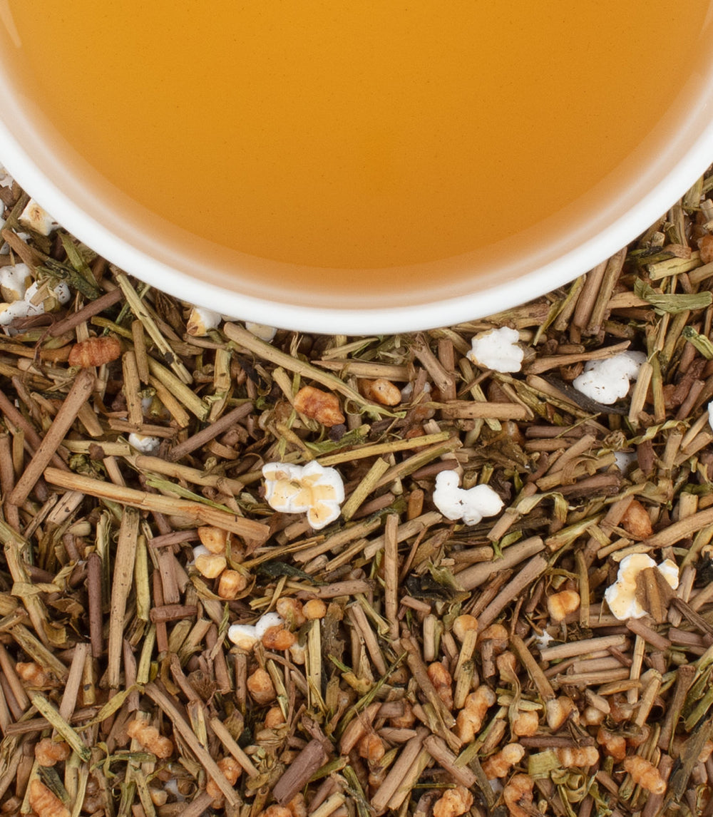 Golden Genmaicha tea with a warm, amber brew surrounded by roasted rice and green tea leaves.