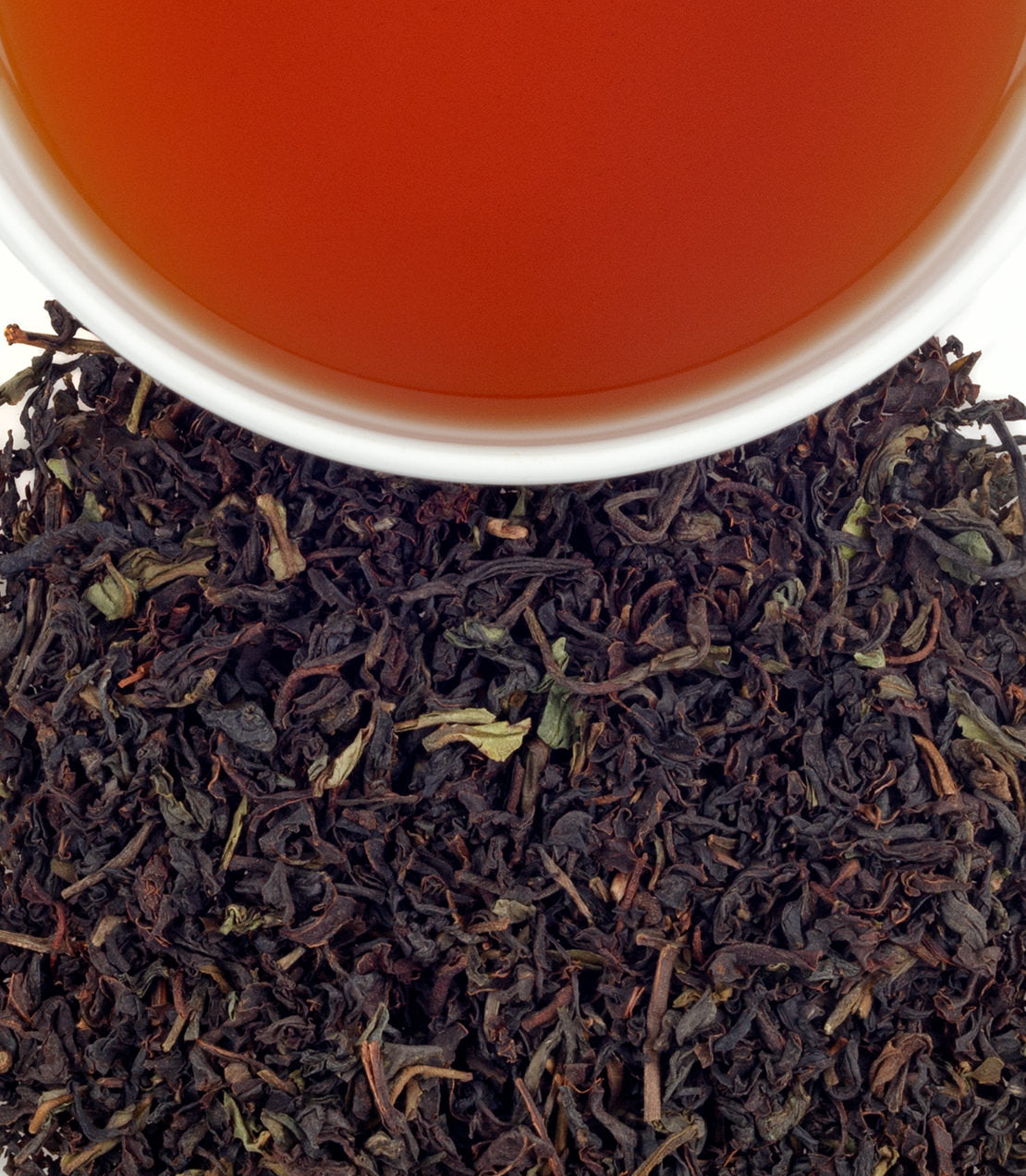 A close-up of All India Blend tea leaves with a cup of brewed tea, showcasing rich colors and textures.