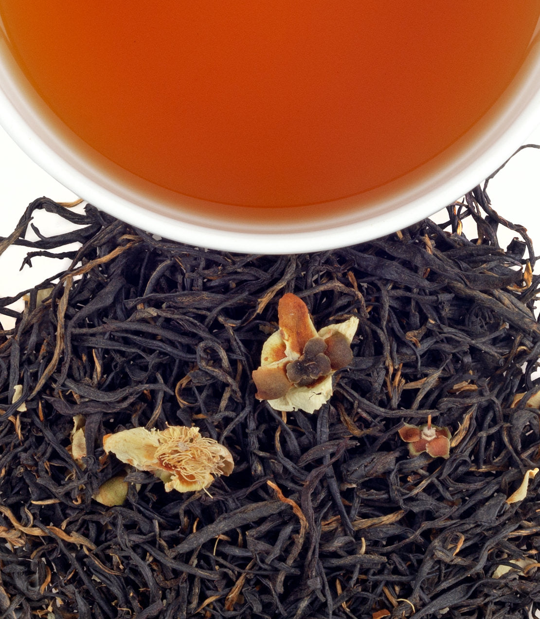 A close-up of Amba Ceylon tea leaves with a cup of brewed tea above, showcasing rich colors and textures.