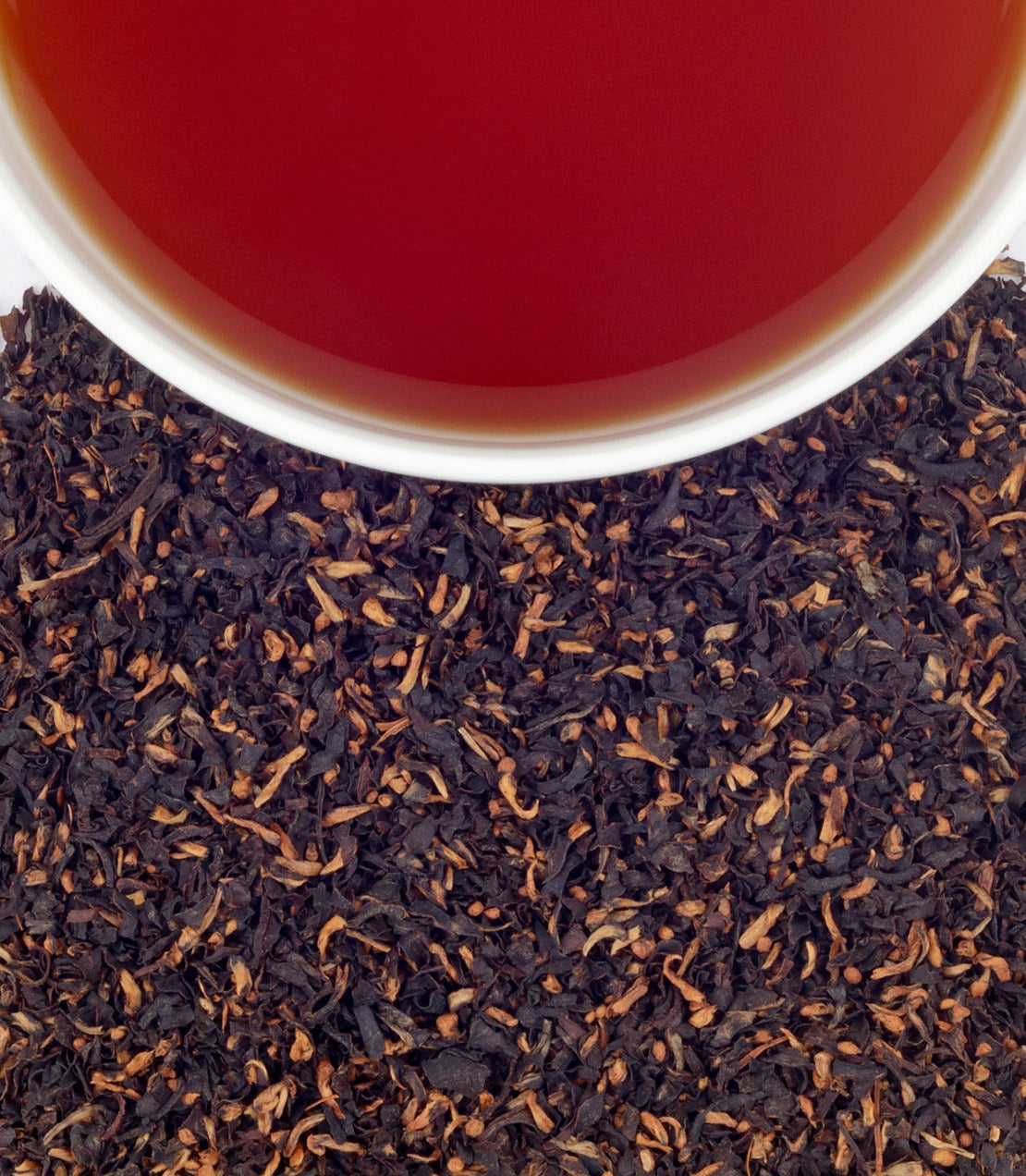 A close-up of Khongea Broken tea leaves with a cup of brewed tea above, showcasing rich color and texture.
