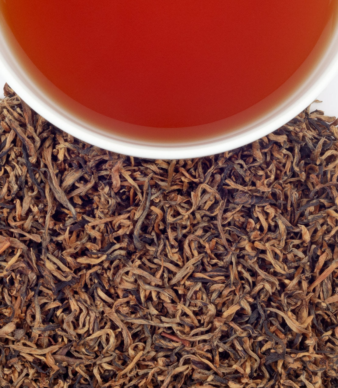 Mokalbari Golden Assam tea leaves with brewed tea in a cup, showcasing rich color and texture.